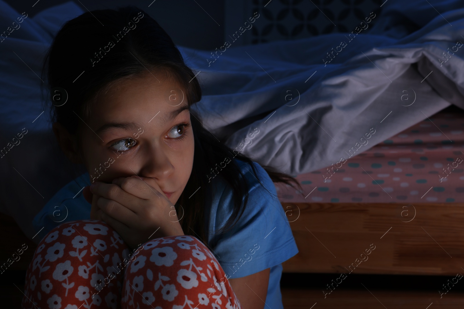 Photo of Afraid girl near bed in her room at night