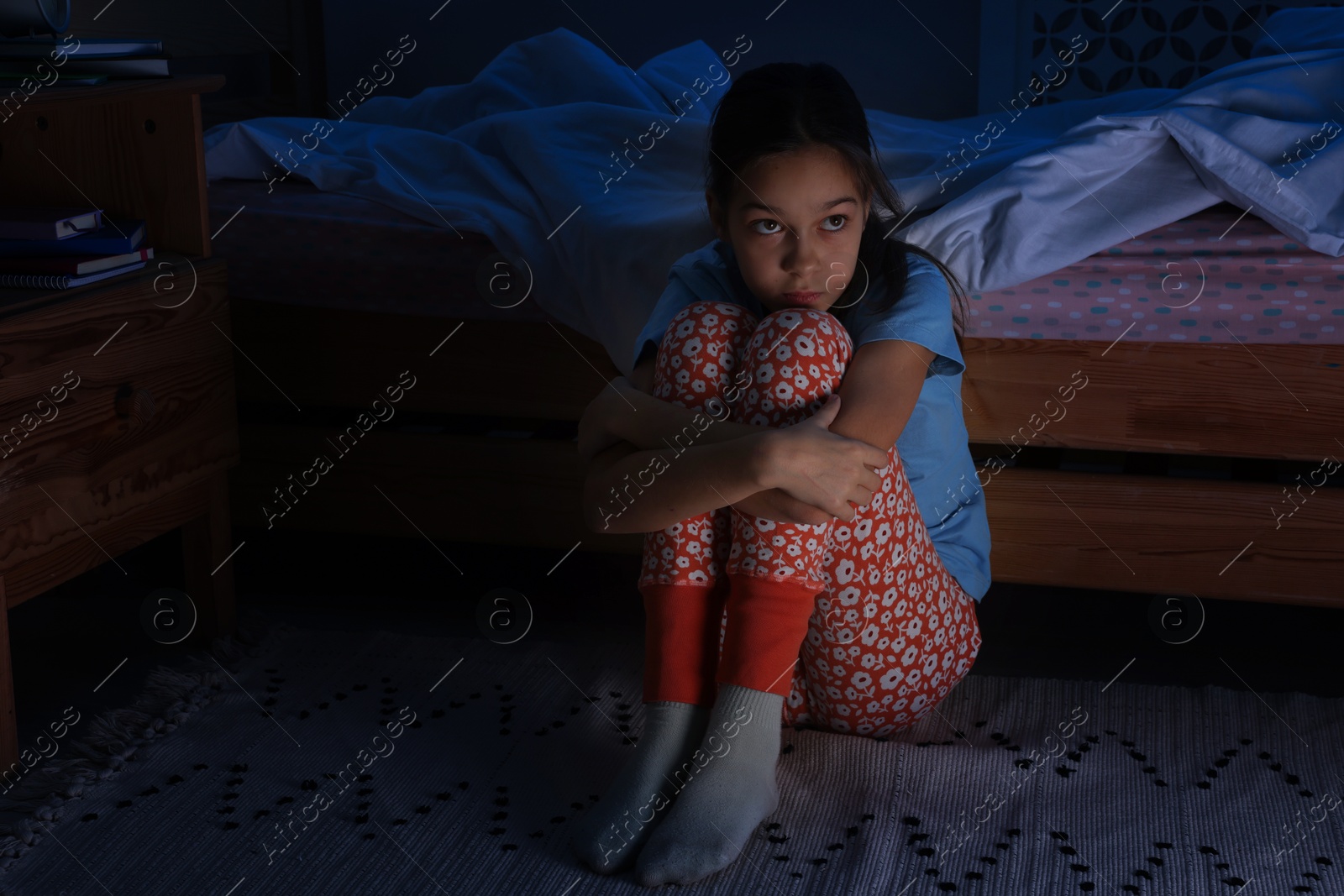 Photo of Afraid girl near bed in her room at night