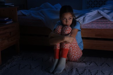 Photo of Afraid girl near bed in her room at night