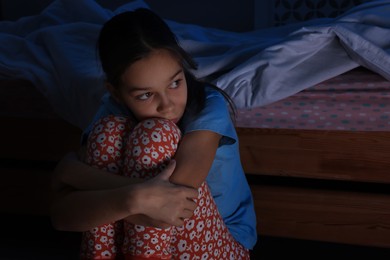 Afraid girl near bed in her room at night