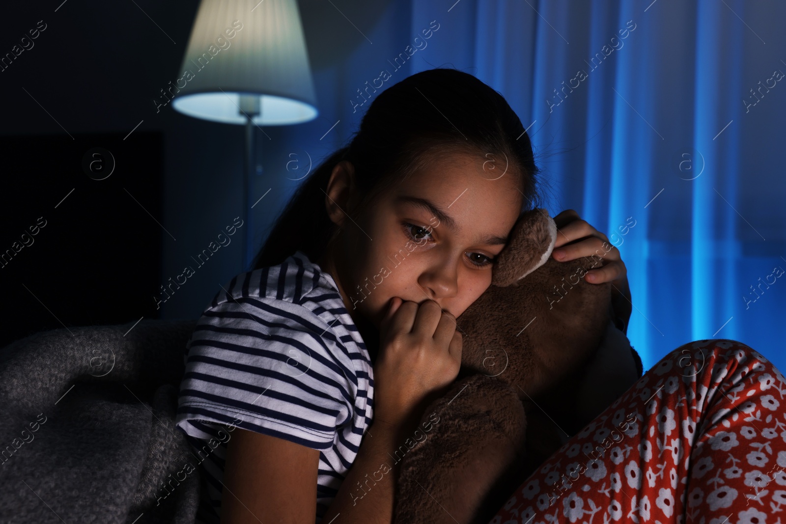 Photo of Afraid girl with teddy bear on sofa at home