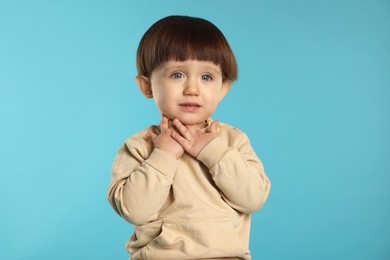 Photo of Portrait of cute little boy on light blue background