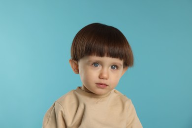 Photo of Portrait of cute little boy on light blue background