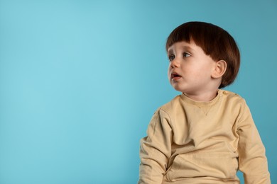 Photo of Portrait of cute little boy on light blue background. Space for text