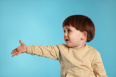 Photo of Portrait of emotional little boy on light blue background