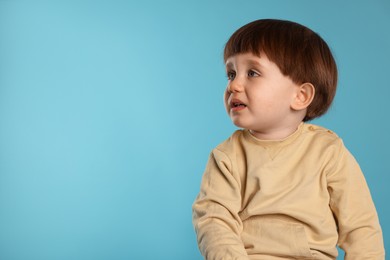 Photo of Portrait of emotional little boy on light blue background. Space for text