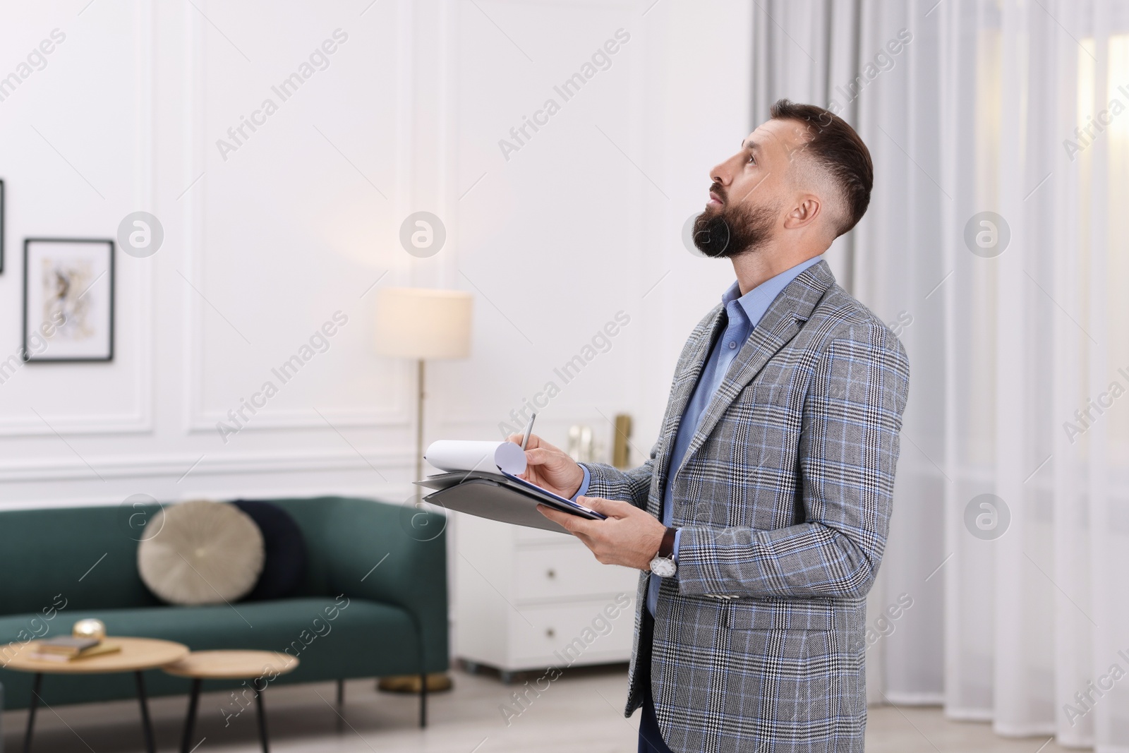 Photo of Real estate appraisal. Inspector with clipboard conducting property valuation indoors, space for text