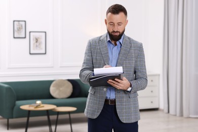 Photo of Real estate appraisal. Inspector with clipboard conducting property valuation indoors, space for text