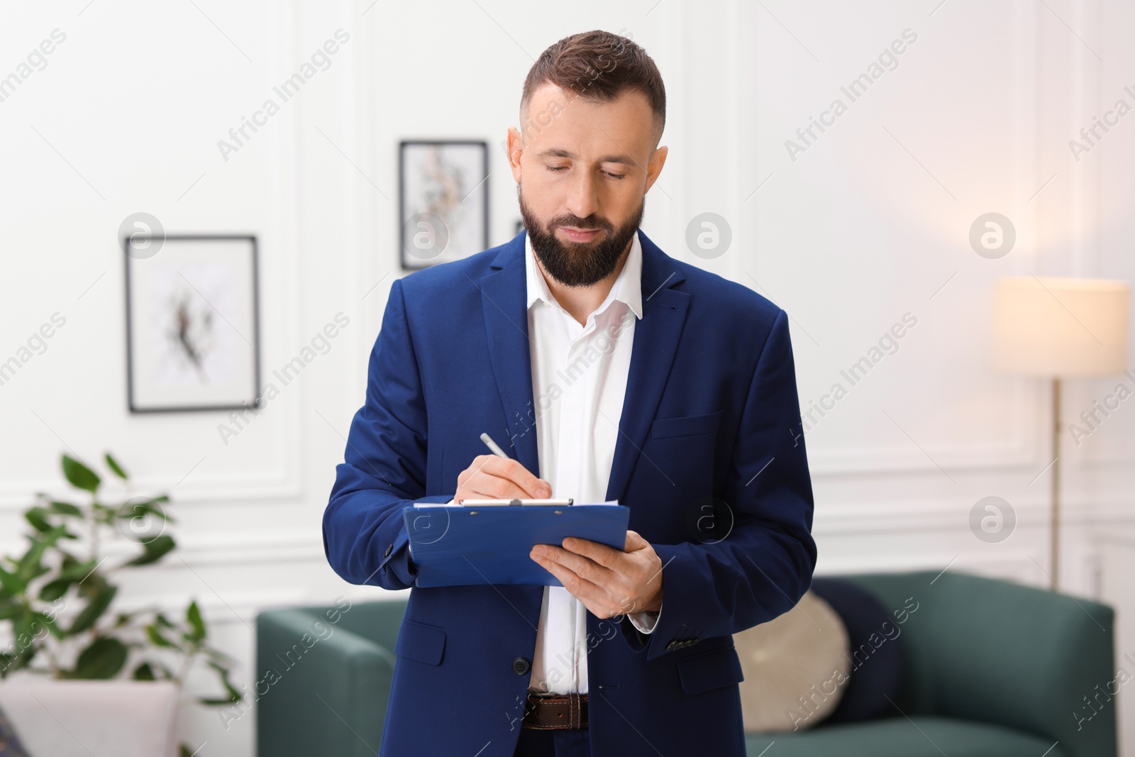 Photo of Real estate appraisal. Inspector with clipboard conducting property valuation indoors