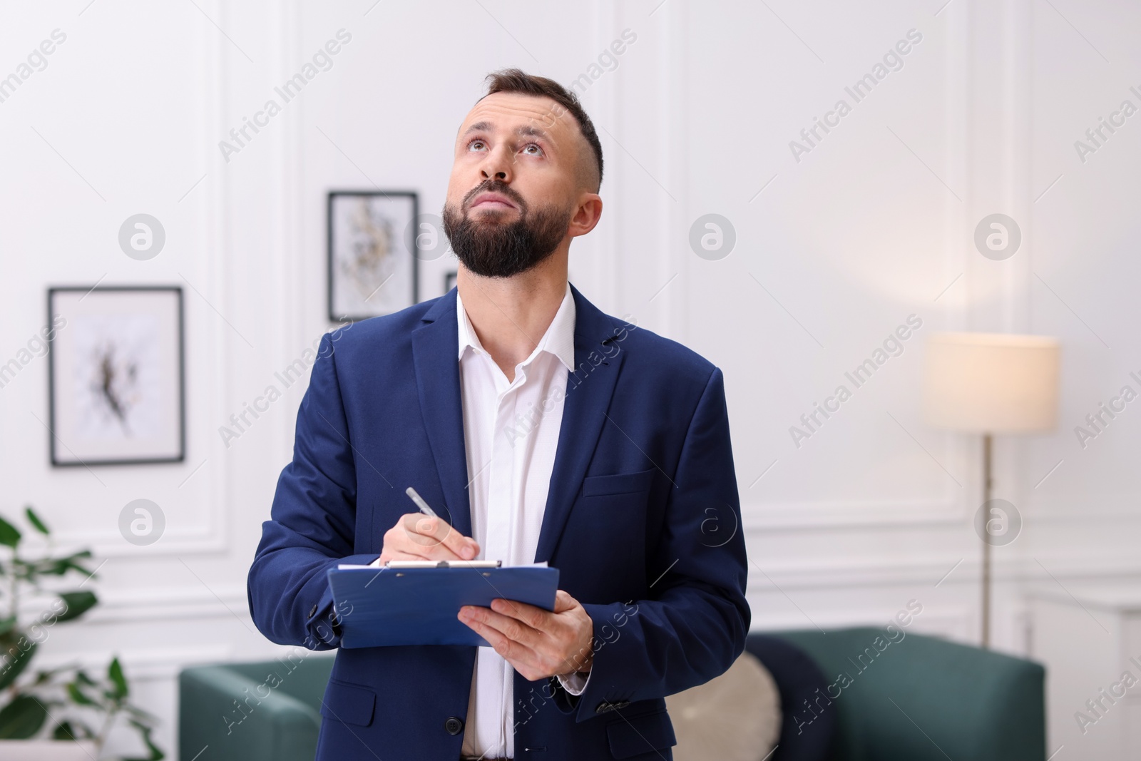 Photo of Real estate appraisal. Inspector with clipboard conducting property valuation indoors