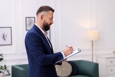 Photo of Real estate appraisal. Inspector with clipboard conducting property valuation indoors. Space for text