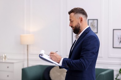 Photo of Real estate appraisal. Inspector with clipboard conducting property valuation indoors. Space for text