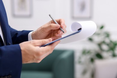 Photo of Real estate appraisal. Inspector with clipboard conducting property valuation indoors, closeup