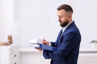 Photo of Real estate appraisal. Inspector with clipboard conducting property valuation indoors