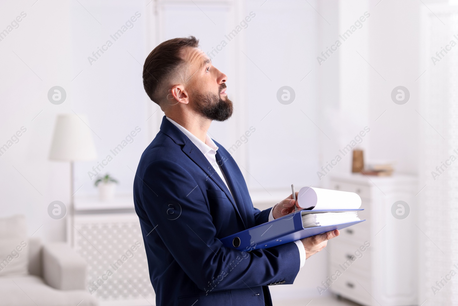 Photo of Real estate appraisal. Inspector with clipboard conducting property valuation indoors