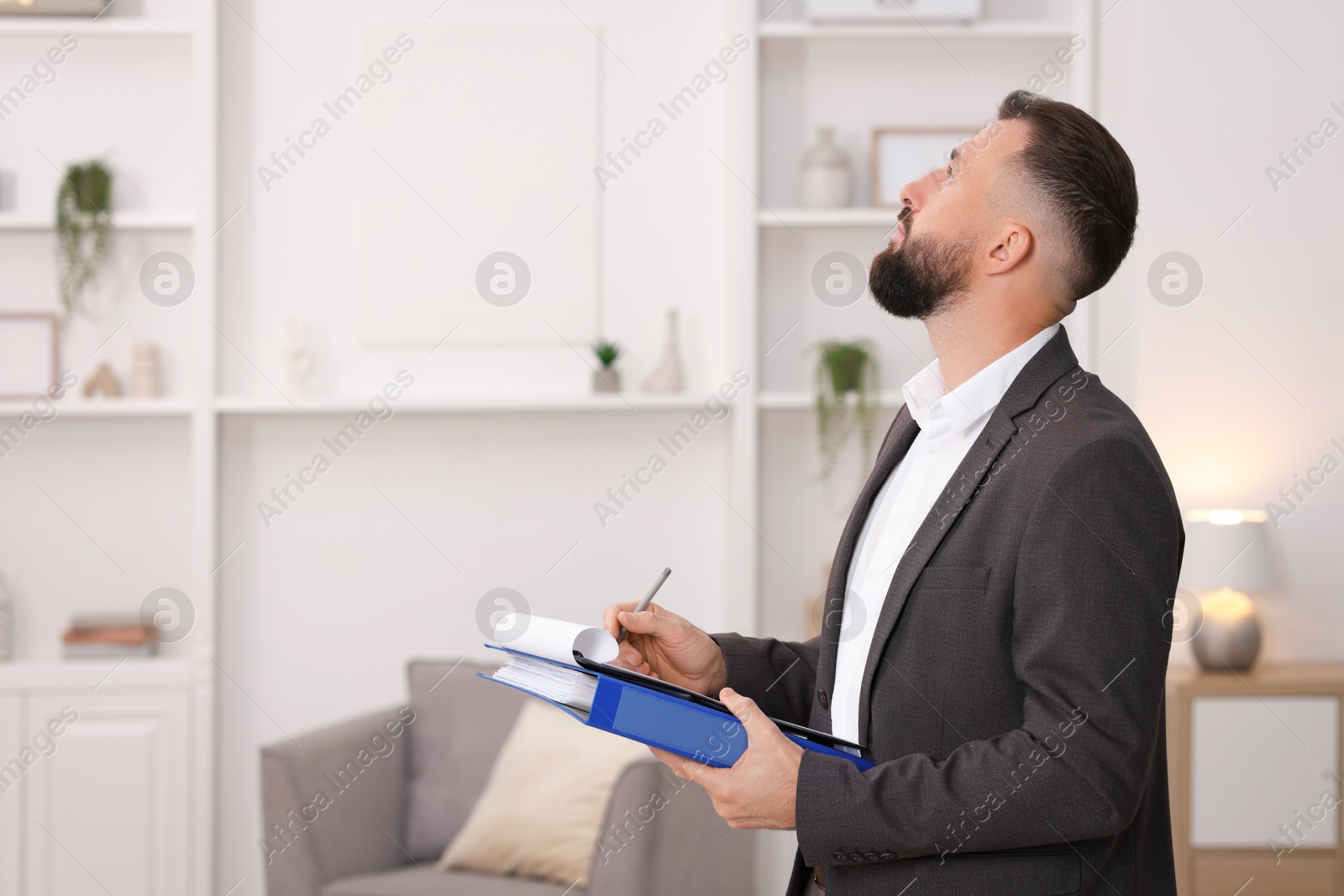 Photo of Real estate appraisal. Inspector with clipboard conducting property valuation indoors, space for text