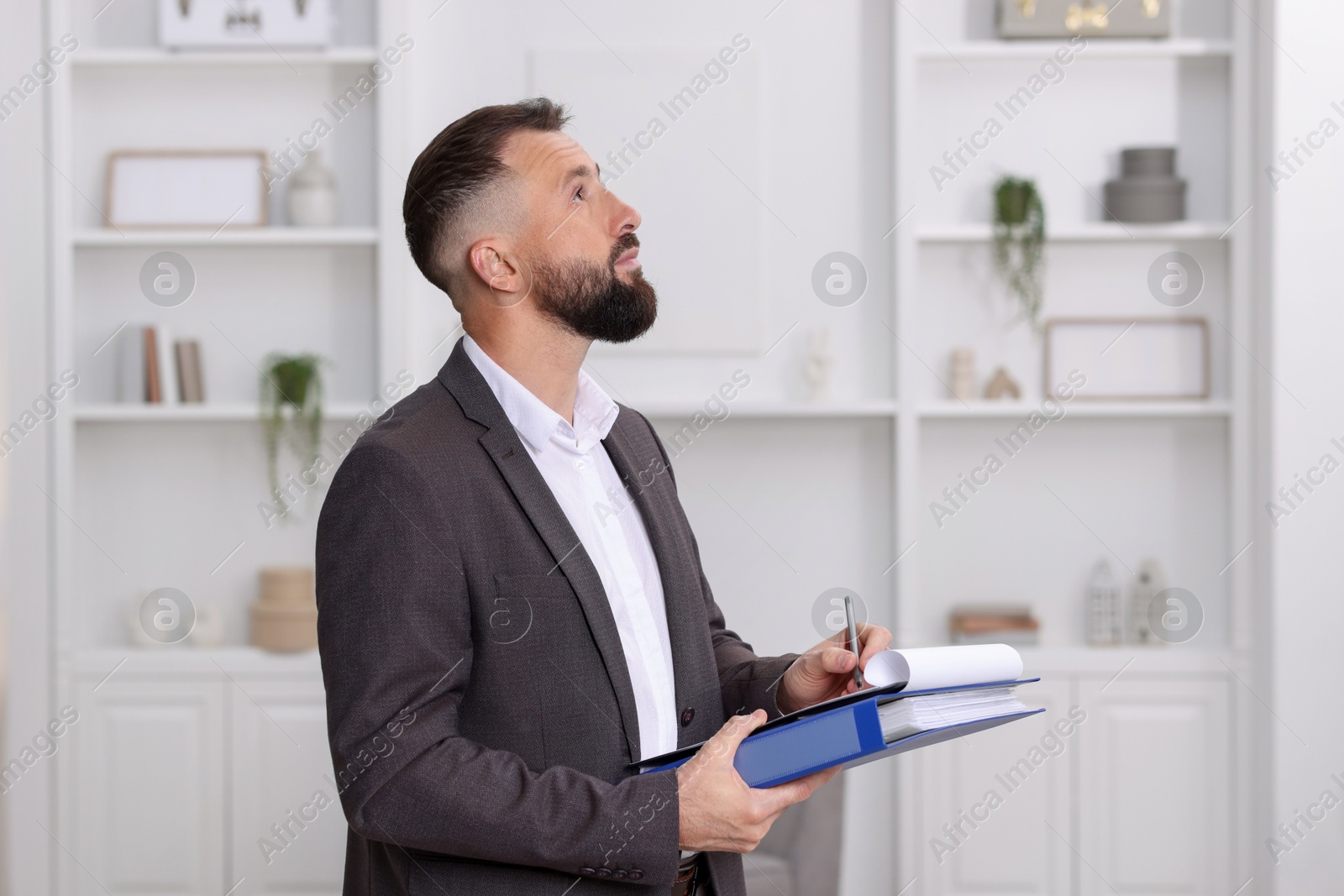 Photo of Real estate appraisal. Inspector with clipboard conducting property valuation indoors