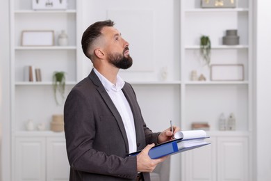 Real estate appraisal. Inspector with clipboard conducting property valuation indoors