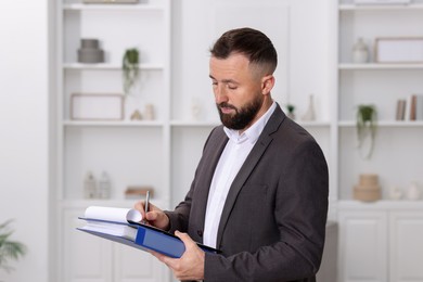 Photo of Real estate appraisal. Inspector with clipboard conducting property valuation indoors