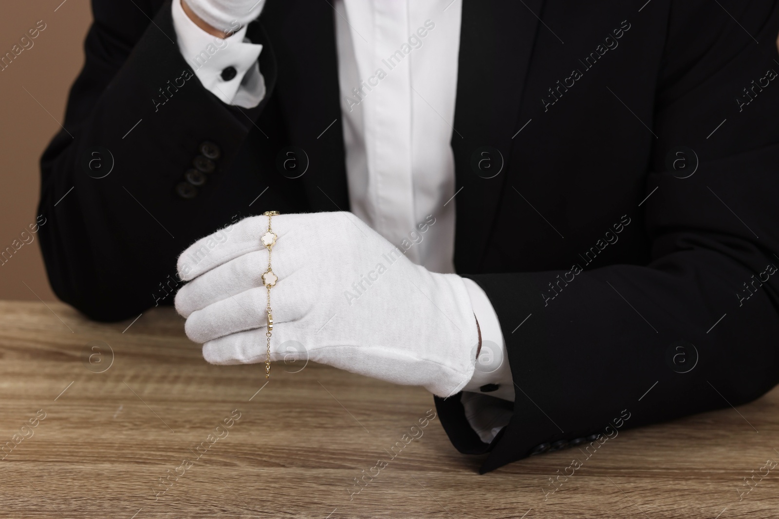 Photo of Appraiser with luxury jewelry at wooden table, closeup