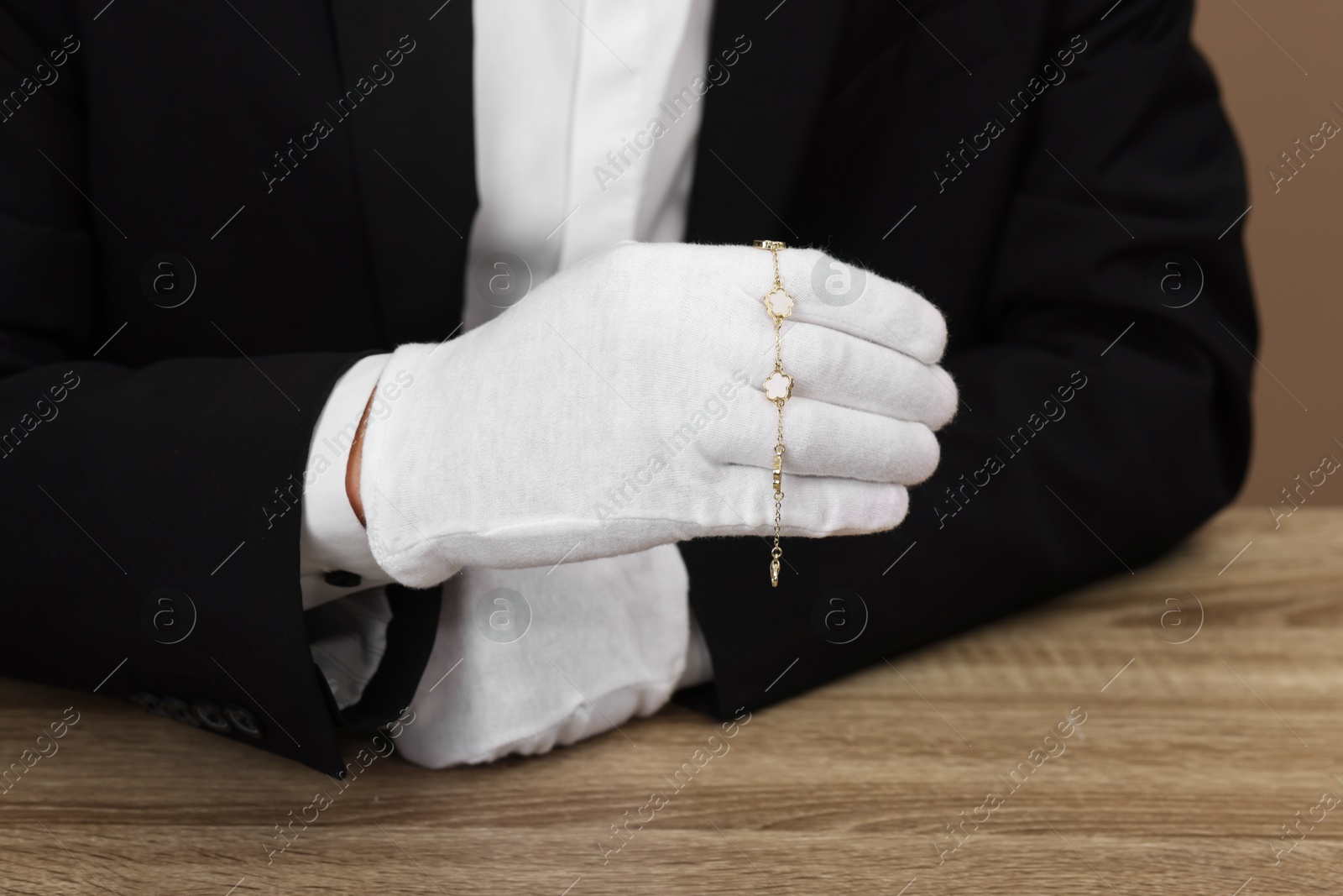 Photo of Appraiser with luxury jewelry at wooden table, closeup