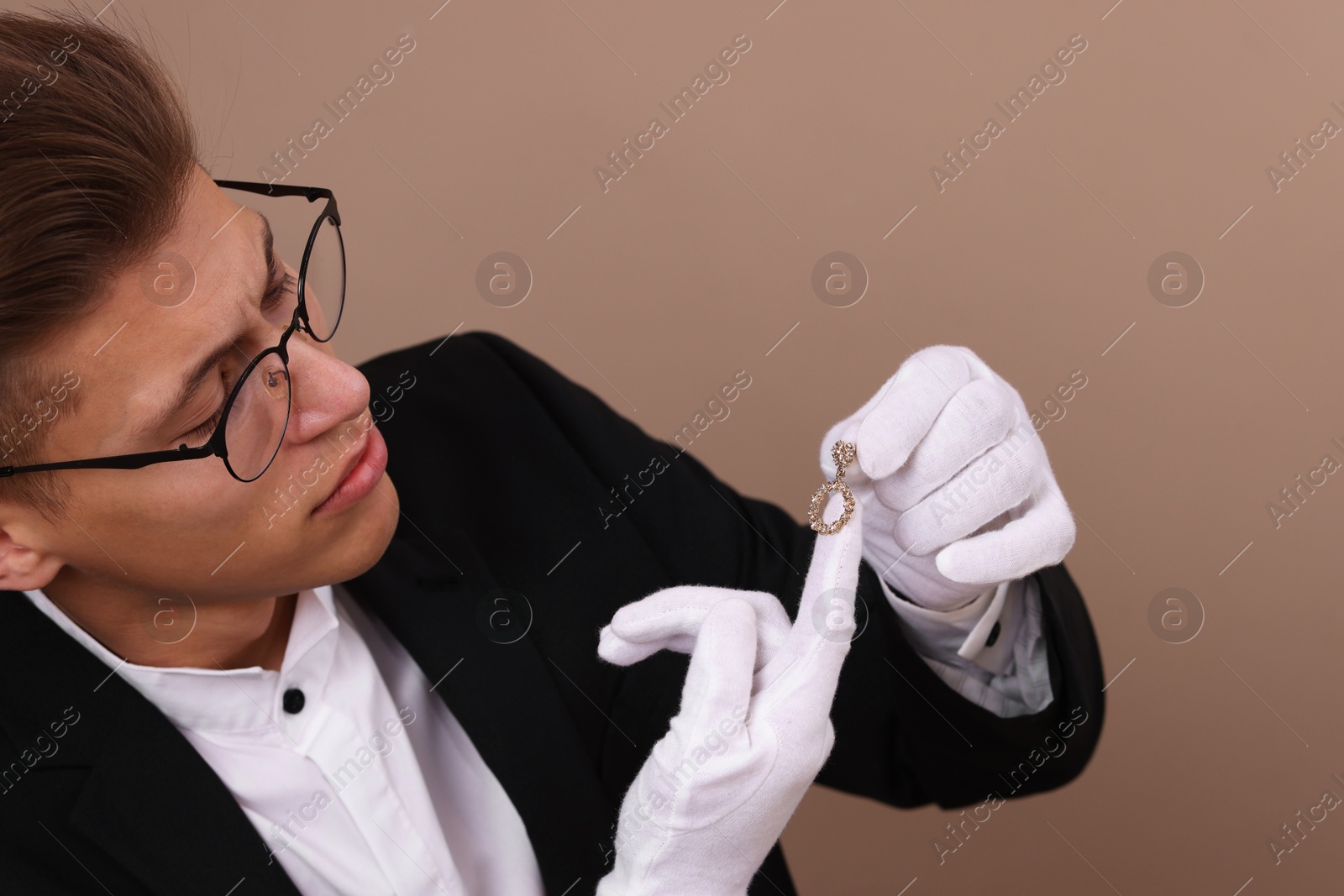 Photo of Appraiser evaluating luxury jewelry on brown background