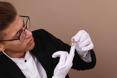 Photo of Appraiser evaluating luxury jewelry on brown background