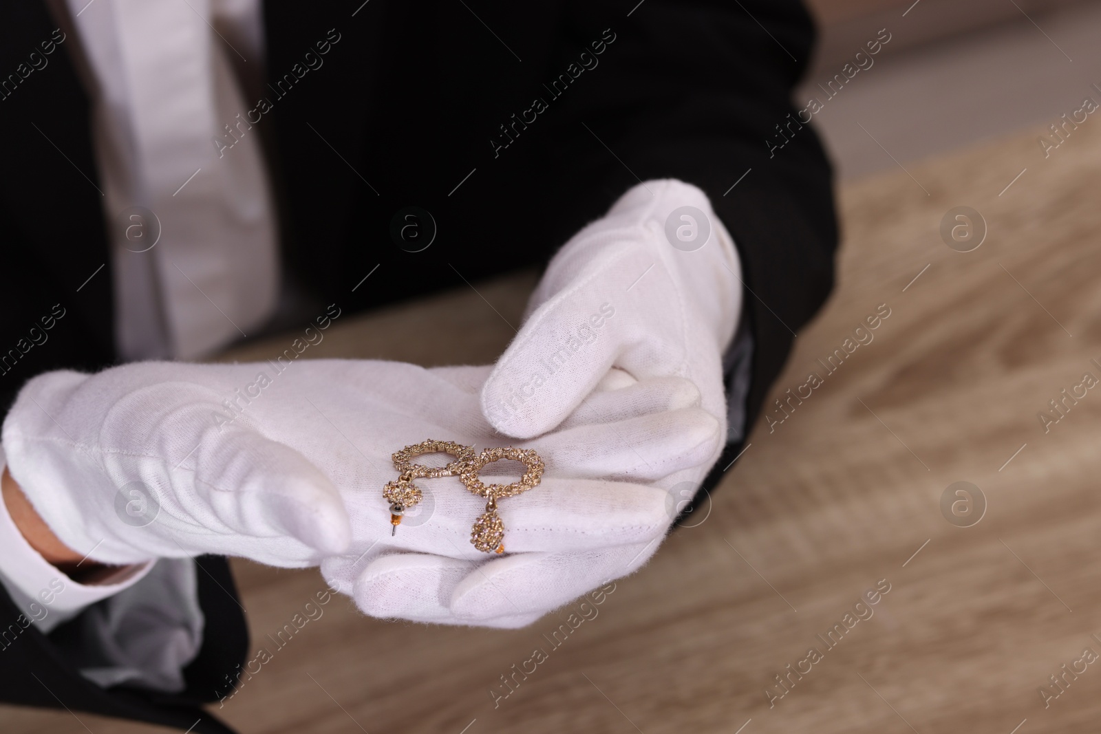 Photo of Appraiser with luxury jewelry at wooden table, closeup