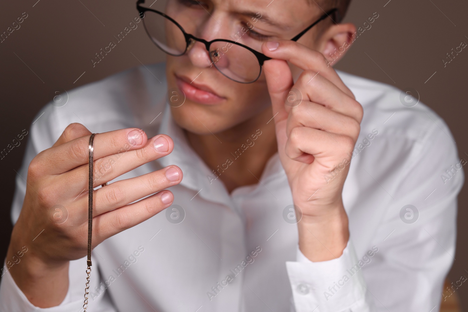 Photo of Appraiser evaluating luxury jewelry on brown background