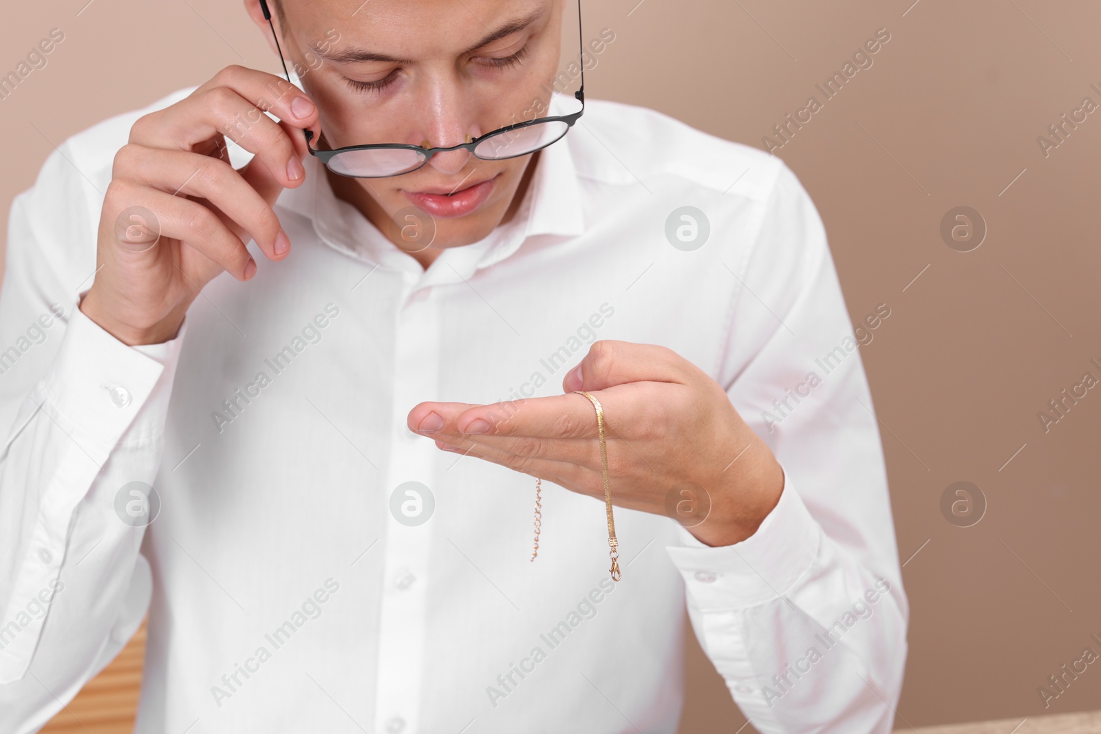 Photo of Appraiser evaluating luxury jewelry on beige background