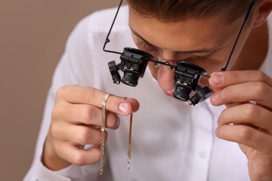 Photo of Appraiser evaluating luxury jewelry on beige background