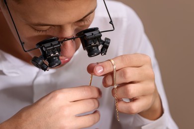 Photo of Appraiser evaluating luxury jewelry on beige background