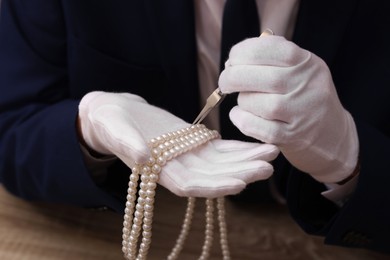 Photo of Appraiser with tweezers evaluating luxury jewelry, closeup