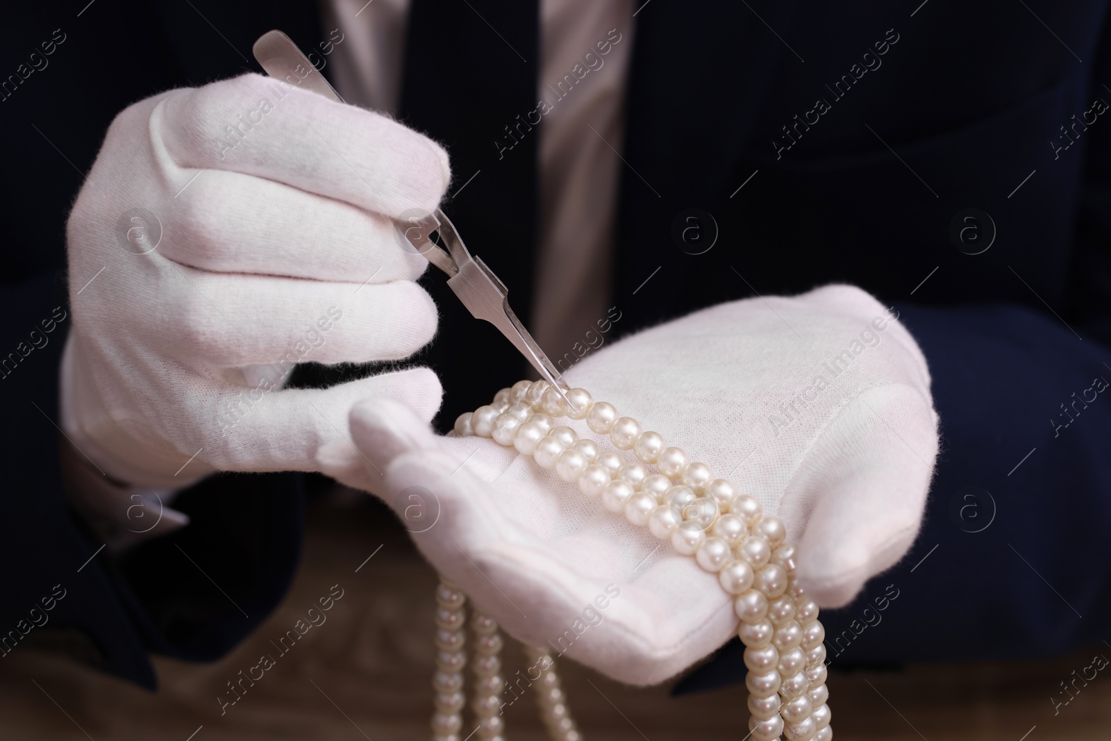 Photo of Appraiser with tweezers evaluating luxury jewelry, closeup