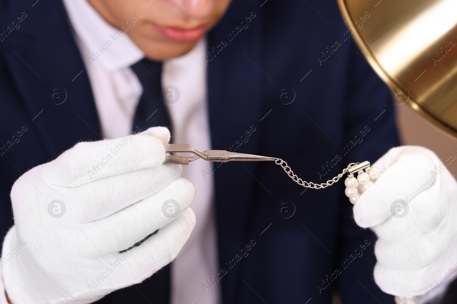 Photo of Appraiser with tweezers evaluating luxury jewelry, closeup