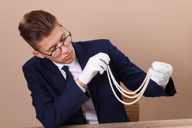 Photo of Appraiser evaluating luxury jewelry on beige background