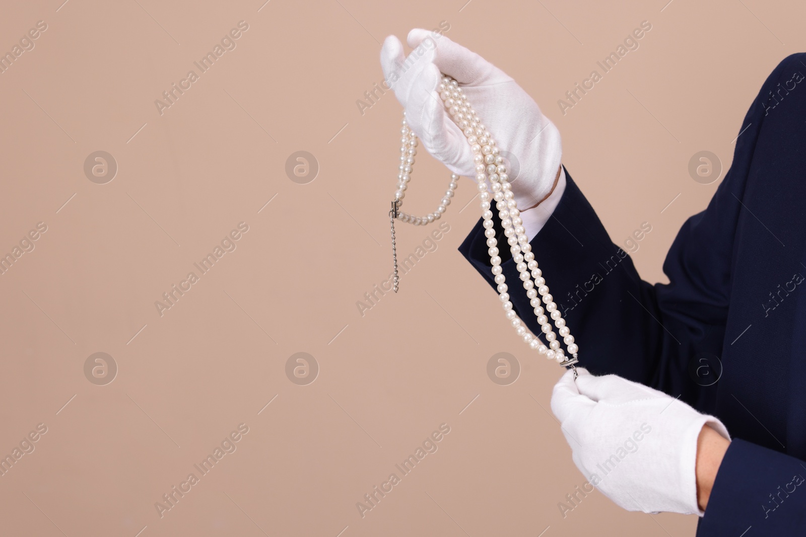 Photo of Appraiser with luxury jewelry on beige background, closeup. Space for text