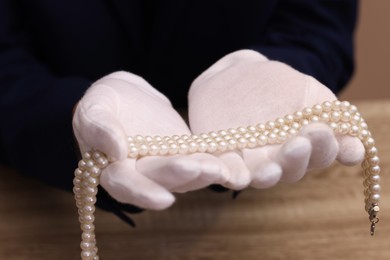 Photo of Appraiser with luxury jewelry at wooden table, closeup