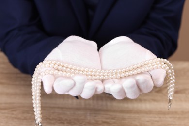 Photo of Appraiser with luxury jewelry at wooden table, closeup