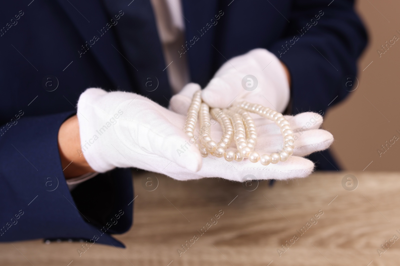 Photo of Appraiser with luxury jewelry at wooden table, closeup