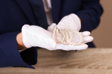 Photo of Appraiser with luxury jewelry at wooden table, closeup