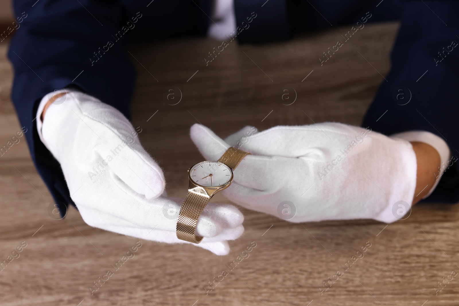 Photo of Appraiser with luxury wristwatch at wooden table, closeup