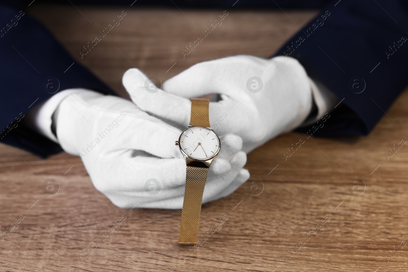 Photo of Appraiser with luxury wristwatch at wooden table, closeup