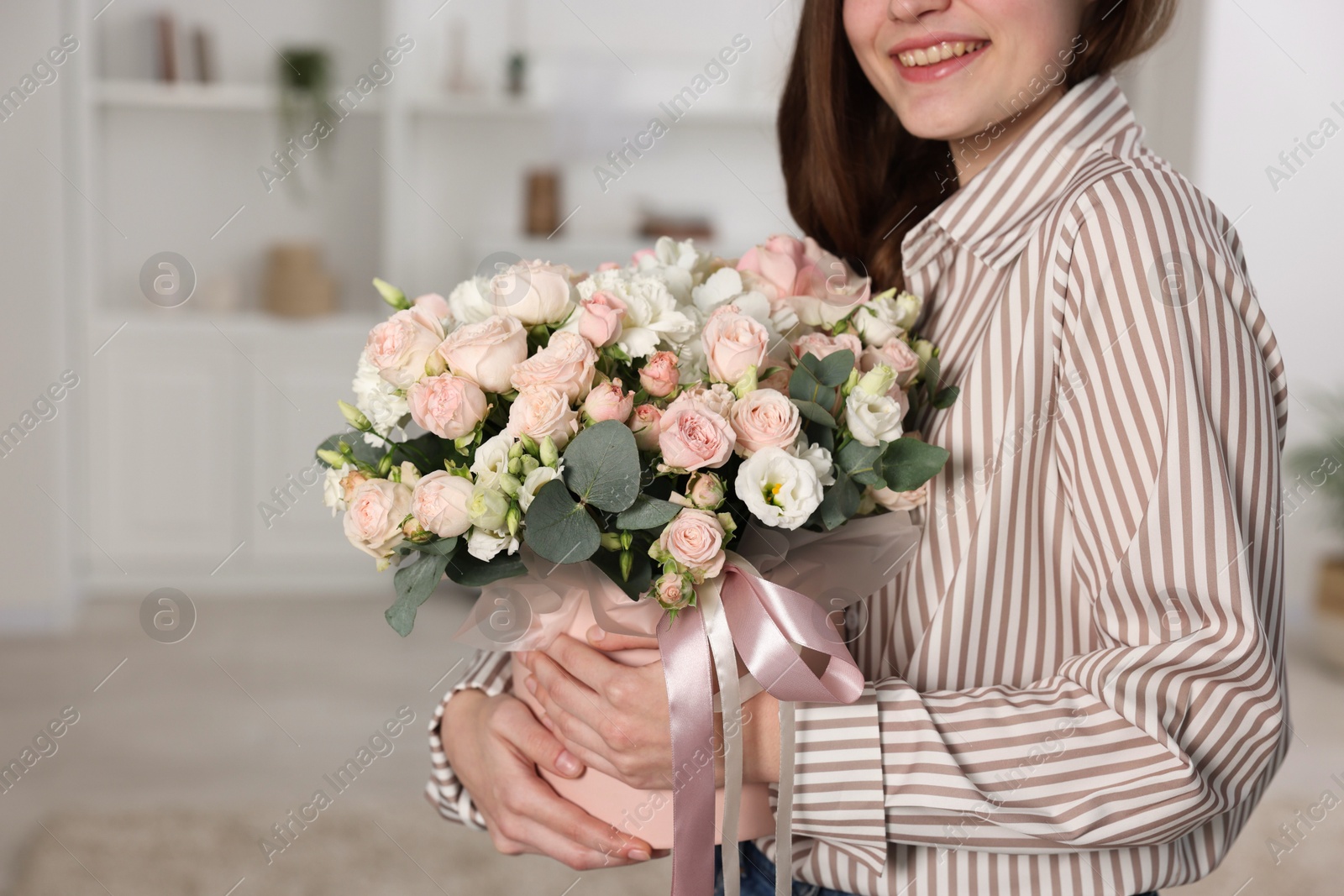 Photo of Smiling woman holding delivered gift box with floral composition indoors, closeup. Space for text