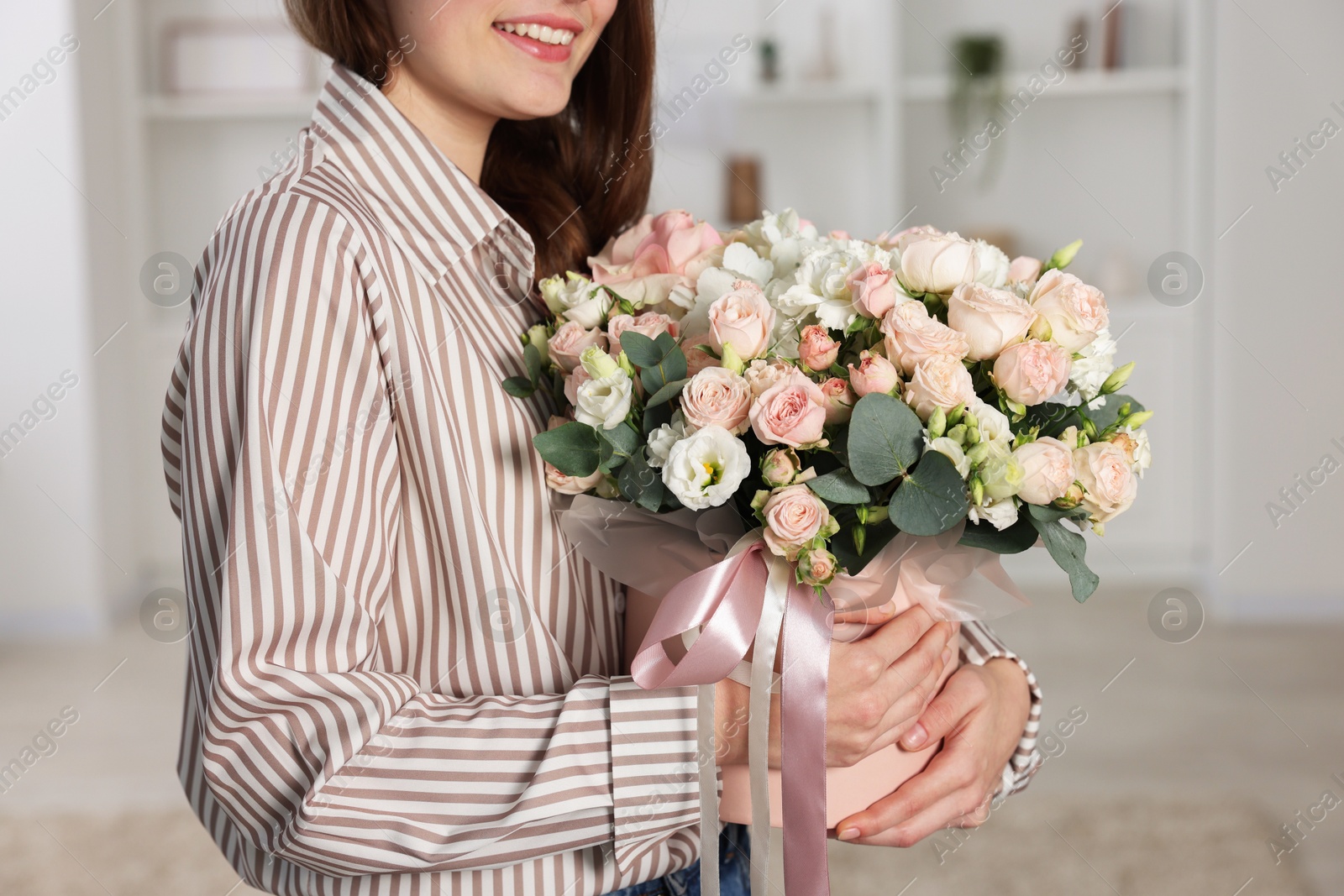 Photo of Smiling woman holding delivered gift box with floral composition indoors, closeup