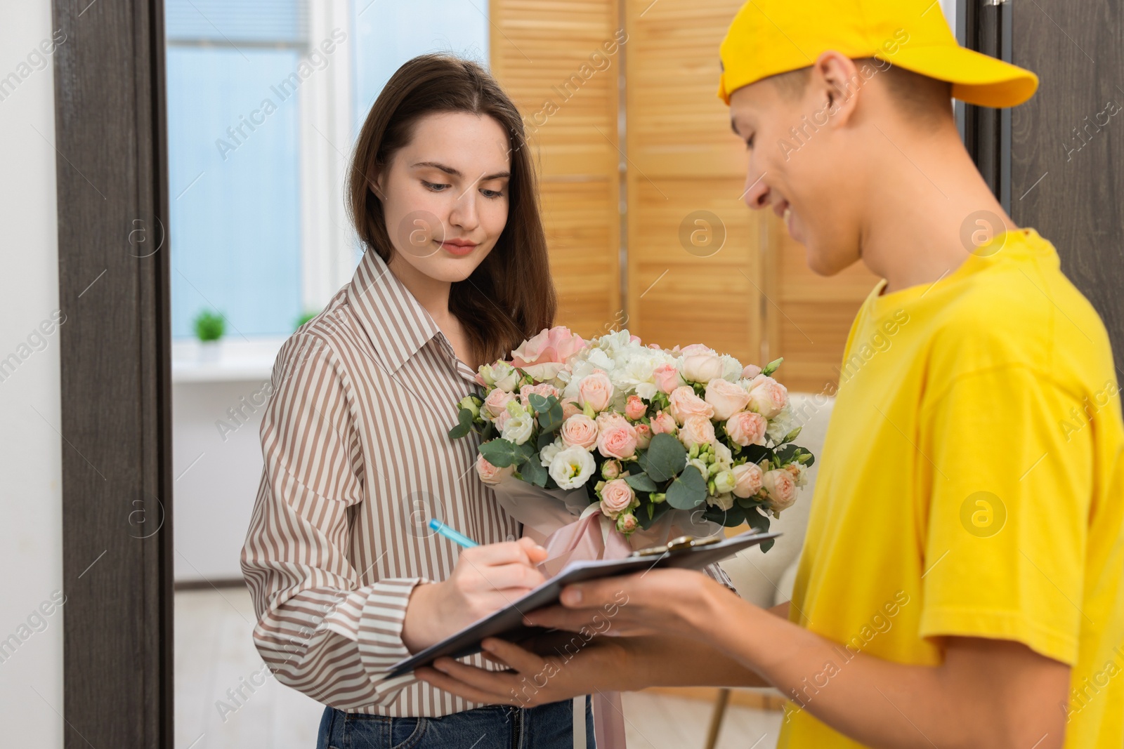 Photo of Woman signing for delivered gift box with floral composition at door