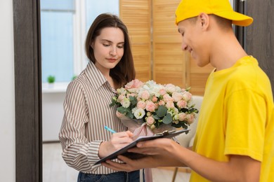 Photo of Woman signing for delivered gift box with floral composition at door