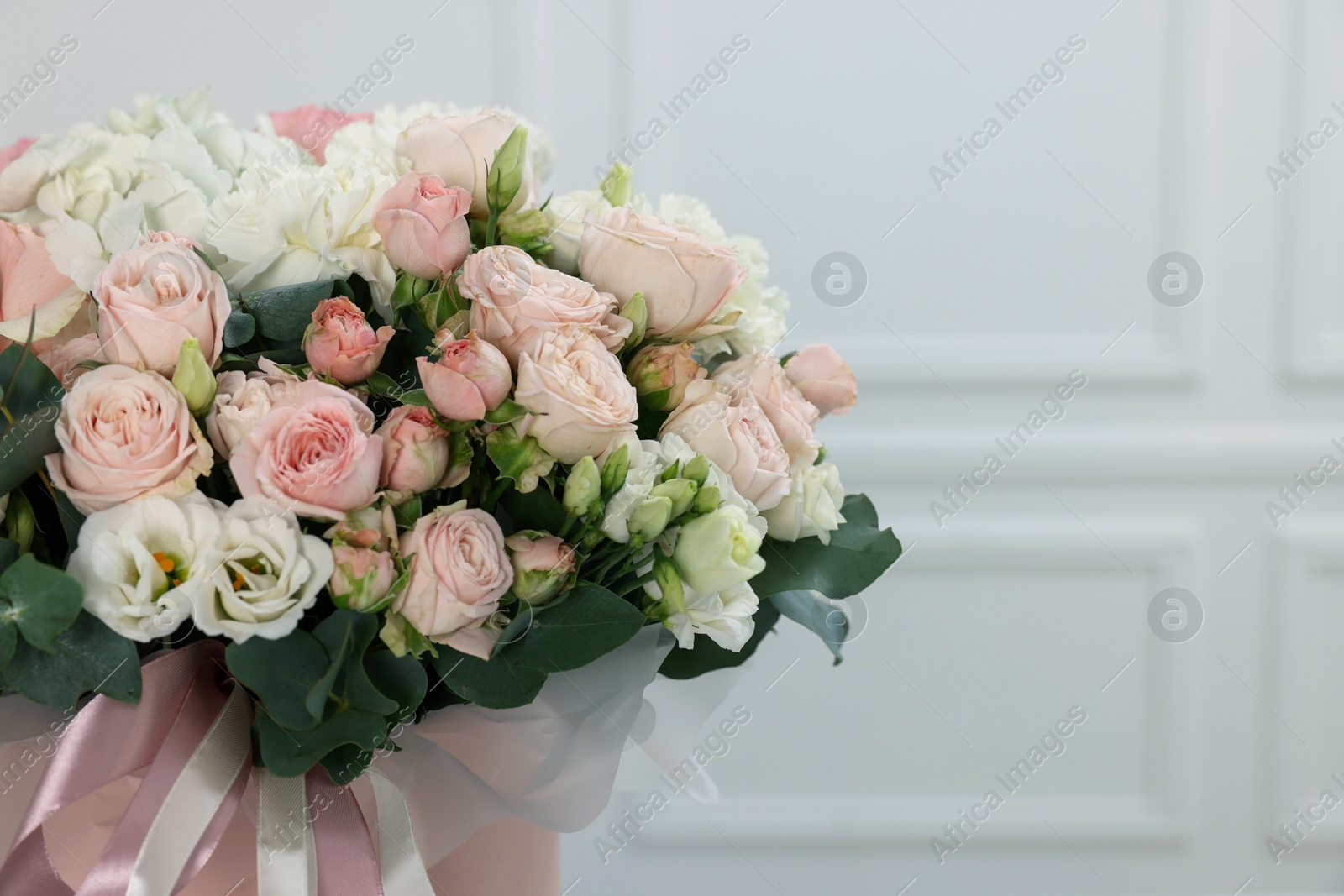 Photo of Bouquet of beautiful flowers and eucalyptus branches against blurred background, closeup. Space for text