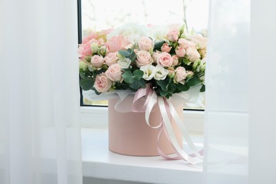 Photo of Gift box with bouquet of beautiful flowers and eucalyptus branches on window sill