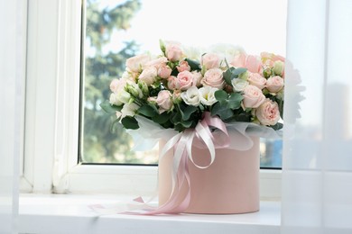 Photo of Gift box with bouquet of beautiful flowers and eucalyptus branches on window sill